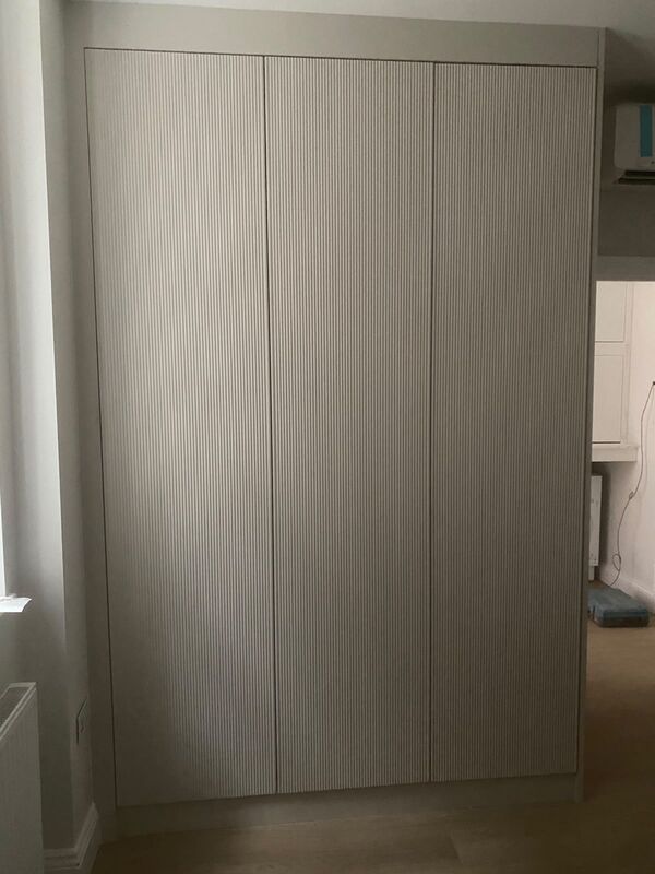 Three-door fluted wardrobe in pale greige, floor to ceiling, handleless