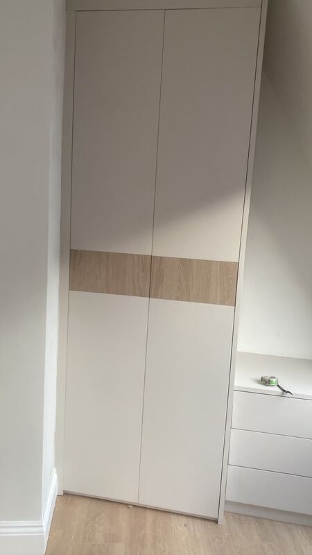 Close detail of cream handleless wardrobe doors with a horizontal oak-effect band